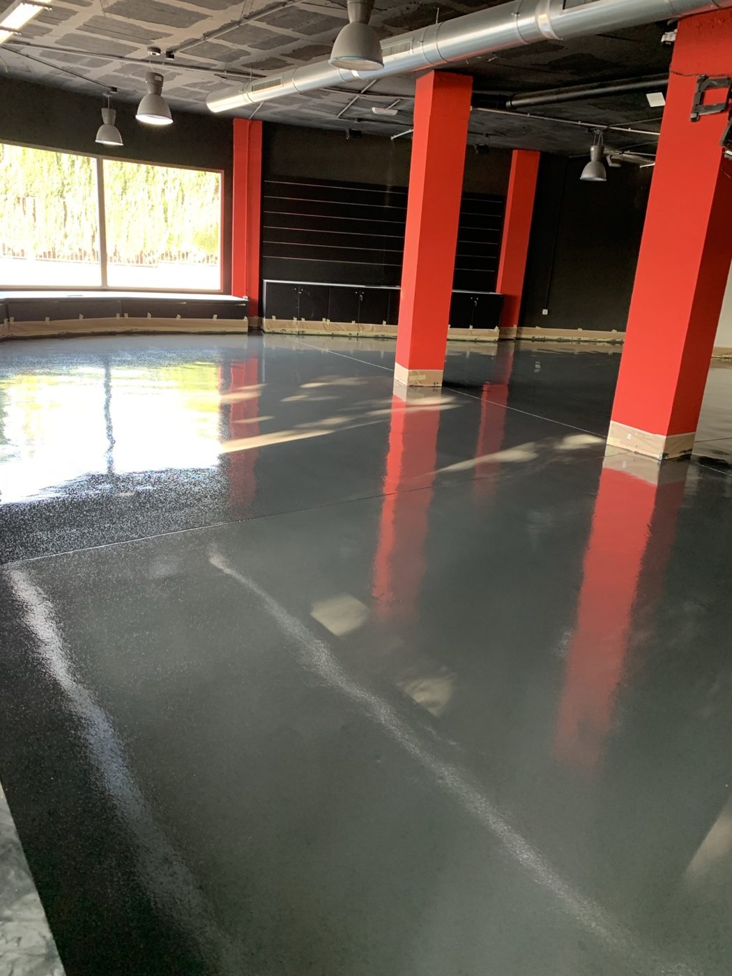 Suelo epoxi gris en un local con columnas rojas