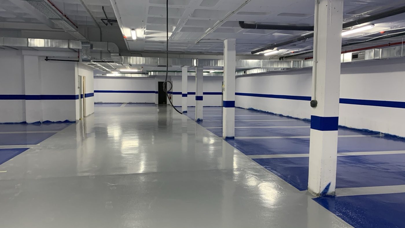 Garaje con revestimiento epoxi gris y plazas azules