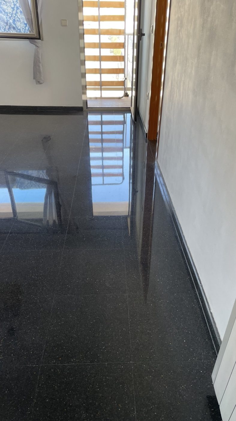 Pasillo de terrazo oscuro con reflejos tras el trabajo